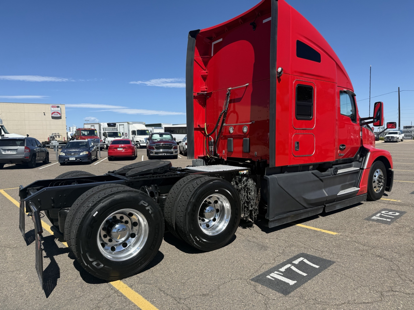 Kenworth T680 sleeper cab tractor in red, side view showing rear axles and chassis; no visible text on components.