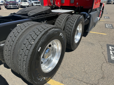 Kenworth T680 rear dual-axle wheels and tires in a truck lot, close-up of dual rear tires and polished aluminum rims.