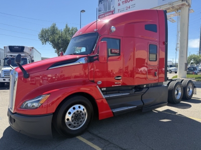Truck cab in red 2023 Kenworth T680 side view with sleeper, engines hood, and tag decals visible