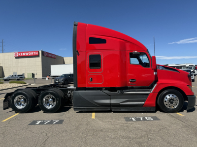 Kenworth T680 sleeper cab side view showing bright red exterior, black lower fairing, and triple-axle rear with chrome wheels.