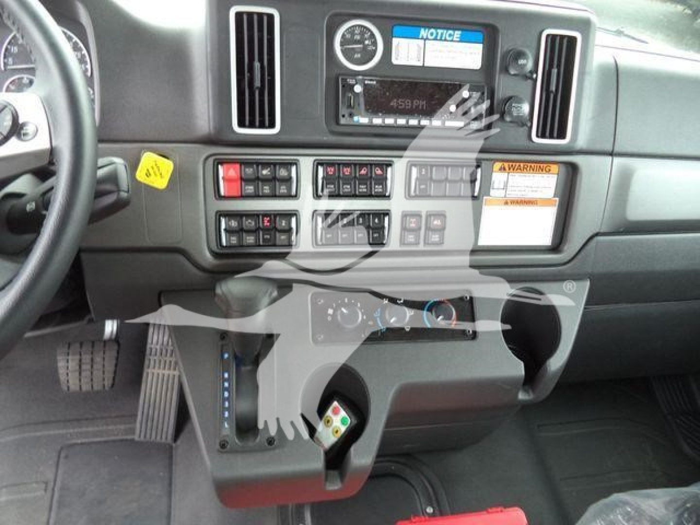 Dashboard interior of a Freightliner M2 106 truck showing center console with gauges, controls, and ignition area.