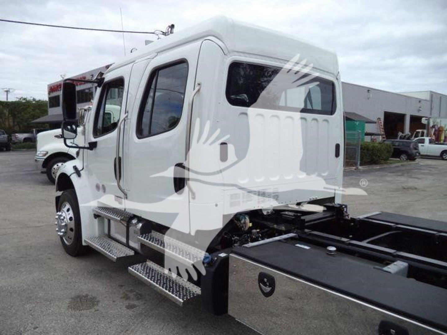Truck cab side view showing Freightliner M2 106 rollback chassis with steps, side rail, and dual rear wheels, stock JU6165.
