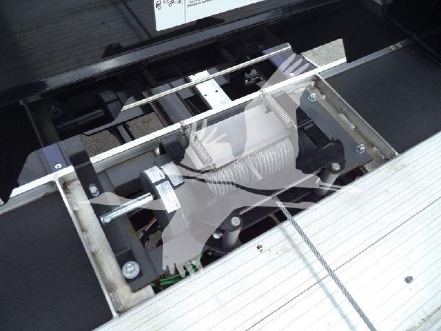 Freightliner M2 106 truck winch/hook area showing suspension and mounting hardware with metal frame and hydraulic lines.
