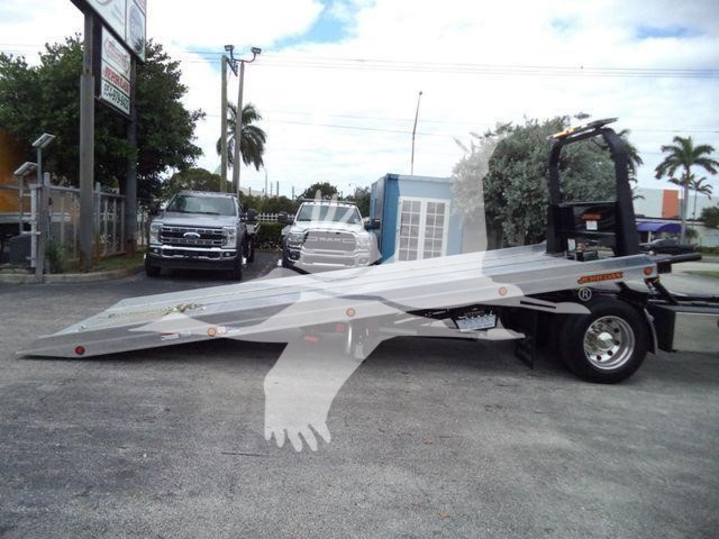 Freightliner M2 106 rollback truck with a lowboy tilt bed in a dealership lot.