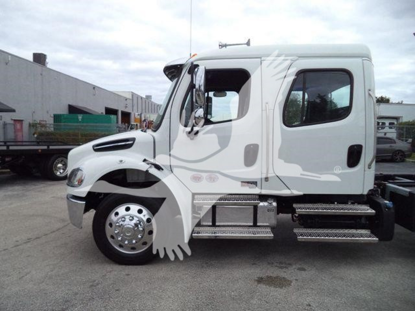 Truck cab side view showing Freightliner M2 106 with rollback equipment and fuel/air tanks