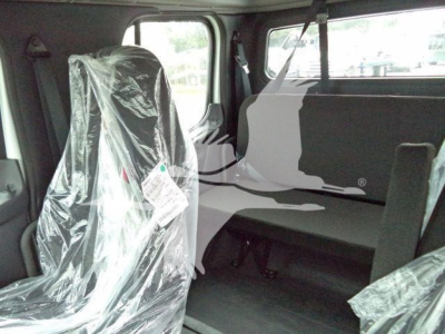 Truck cab interior showing plastic-wrapped seats and seating area with bench/organizer and windows; Freightliner M2 106 stock visual in a showroom or lot.