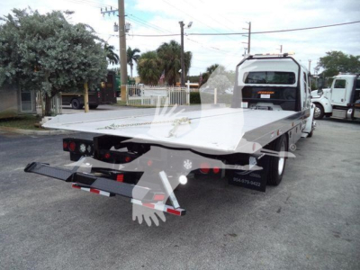 Flatbed tow truck bed at rear view showing hydraulic equipment and rear bumper.