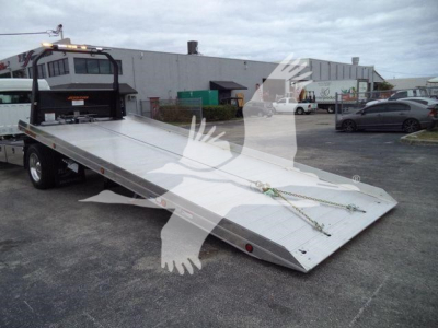Flatbed tow truck bed with ramps and chains in the foreground; Freightliner M2 106 listing details shown in the image.