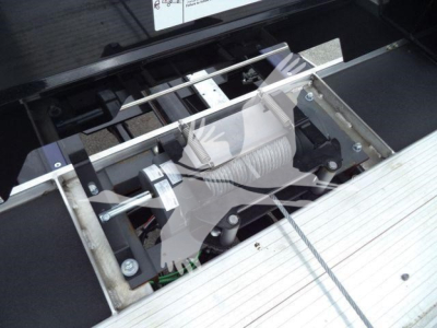 Freightliner M2 106 truck winch/hook area showing suspension and mounting hardware with metal frame and hydraulic lines.