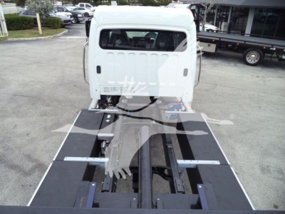 Truck cab exposed from rear showing a flatbed/frame of a 2027 Freightliner M2 106 rollback chassis, white cab with black platform, engine bay hidden, dealership lot in background.