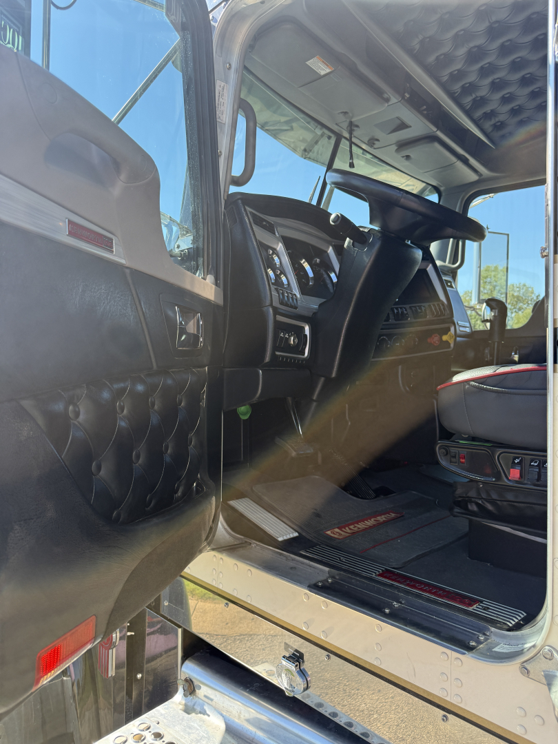 Kenworth W900L cab interior view showing driver seat and dashboard in a conventional sleeper truck.