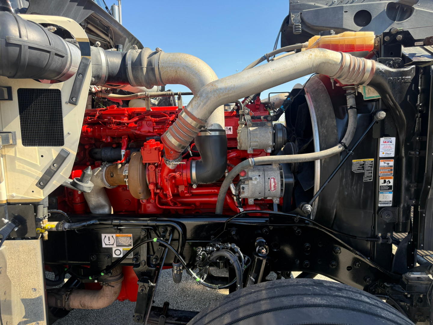 Kenworth W900L engine bay with red engine and large intake/exhaust piping visible.