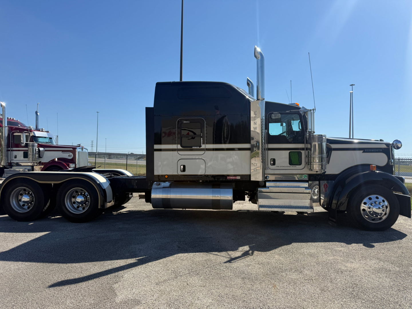 Kenworth W900L sleeper conventional truck side view showing chrome fuel tanks and exhaust stacks with black and gray paint