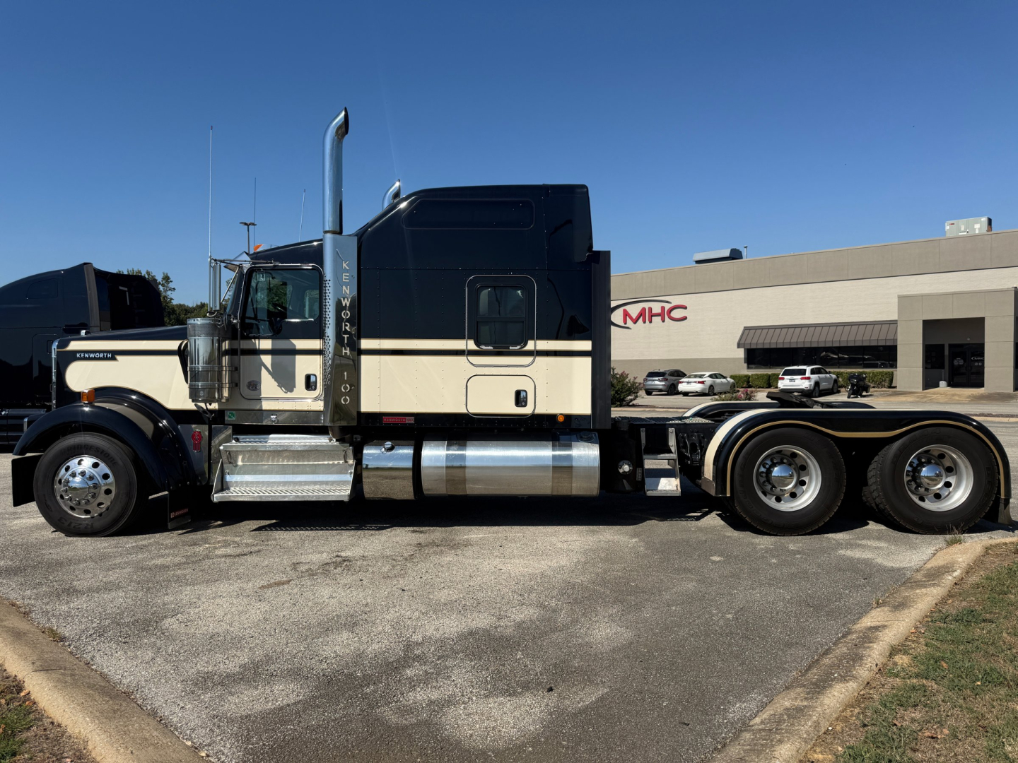 Kenworth W900L conventional sleeper truck side view showing chrome fuel tanks and dual rear axles.