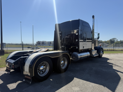 Kenworth W900L conventional sleeper truck, side and rear view showing dual rear axles, fuel tanks, and exhaust stack.