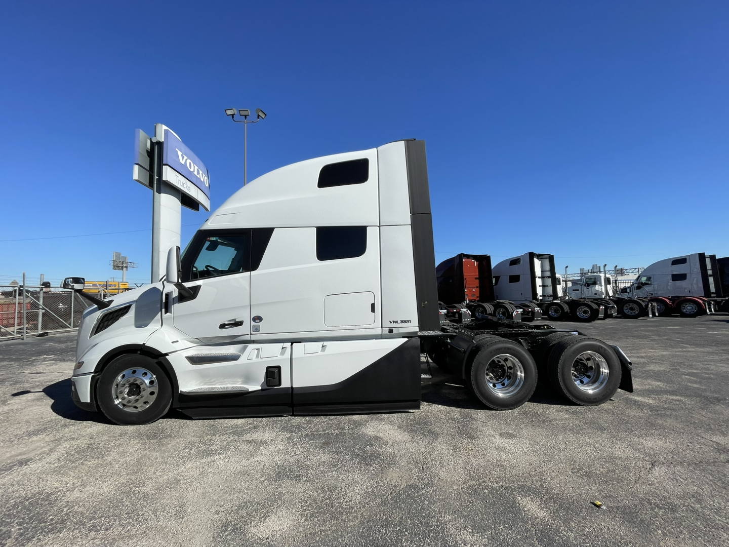 Volvo VNL64T860 tractor-trailer side profile showing sleeper cab and triple rear axles, clean white paint with black lower trim.