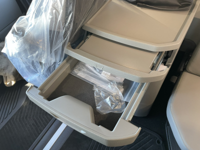 Truck cab interior showing open pull-out storage drawers with light gray trim and plastic protective wrap.