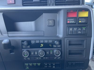 Dashboard and control panel of a Volvo VNL64T860 sleeper cab showing HVAC controls, USB-C/EA port, hazard switch, and various indicator lights.