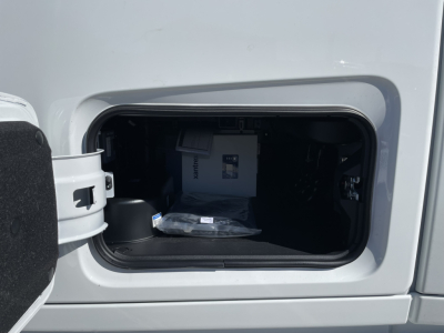 View into a Volvo truck cab storage area showing a small battery or electronic module with packaging inside the storage compartment.