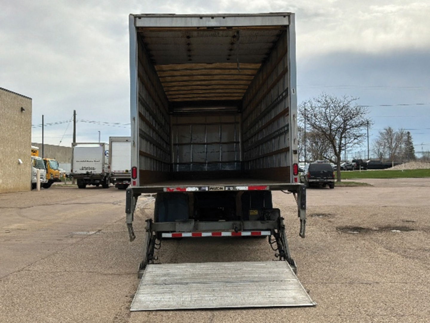 Truck trailer with lowered aluminum ramp, open cargo area, rear view showing empty inside cargo box of a 2020 Hino 268 conventional daycab.