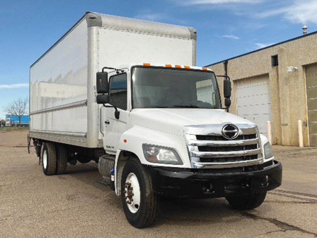 Hino 268 conventional daycab truck with a large box trailer attached, front grille and bumper visible, white cab and box.
