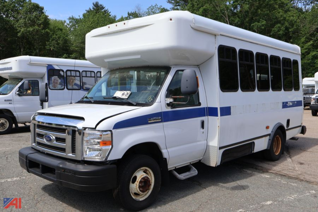 2017 Ford E350 wheelchair bus in a parking lot, side windows, front grille, bus body with blue stripe, raised roof, OEM wheels.