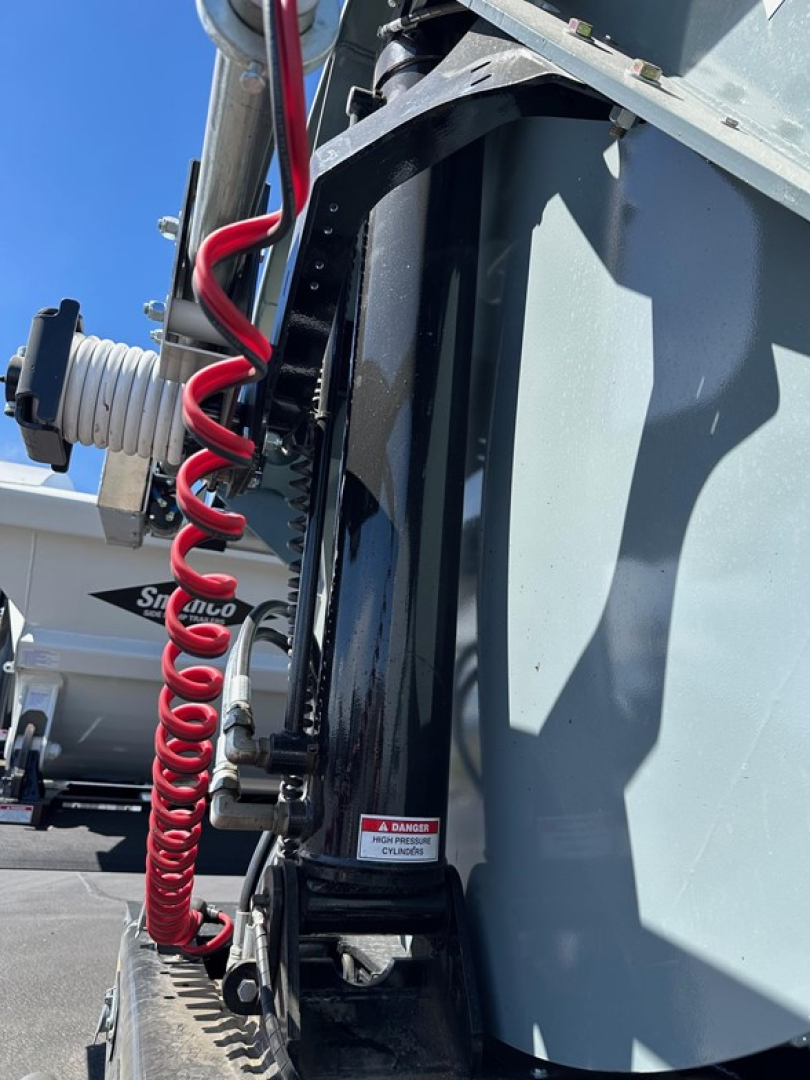 Smithco air ride side dump trailer showing hydraulic hoses and mounting frame with warning label