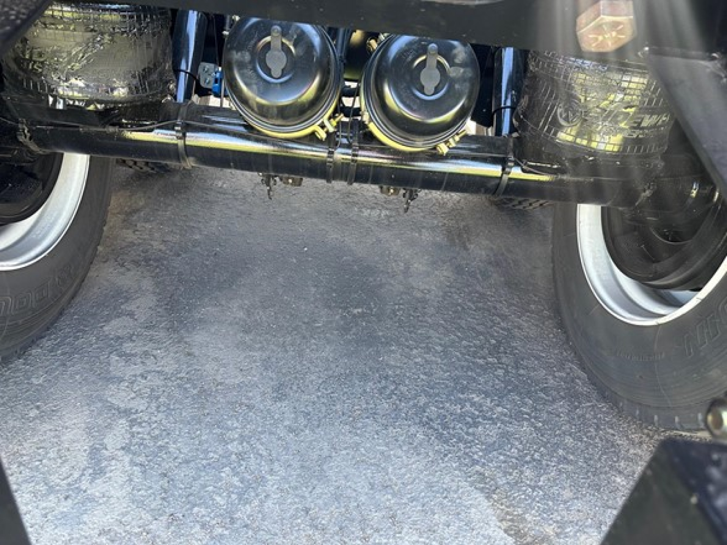 Trailer undercarriage view showing axles and air ride components with dual wheels and suspension hardware.