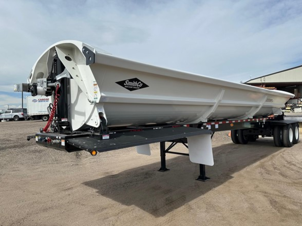 Smithco air ride side dump trailer showing tilt mechanism and hydraulic lines with Smithco logo on side panel.