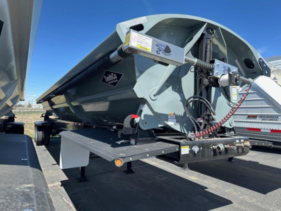 Dump trailer side view showing pneumatic air ride mechanism and hydraulic support components with Safety decals and label stickers.