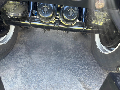 Trailer undercarriage view showing dual air ride system components and axles, with chrome exhaust/piping and suspension elements visible between tires.