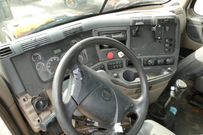 Dashboard/driver area of Freightliner Cascadia 125 truck cab showing steering wheel, gauges, control panel, and gear shifter.