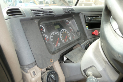 Dashboard of a Freightliner Cascadia 125 truck showing analog gauges, steering wheel, and dash panel in view.