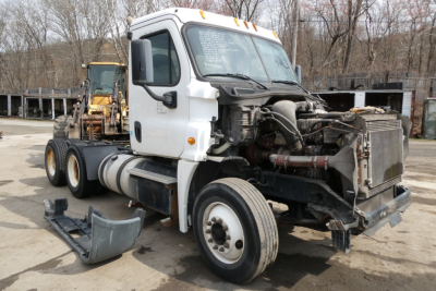 Freightliner Cascadia 125 daycab truck with exposed engine and front end components, white cab, missing bumper and hood area open.