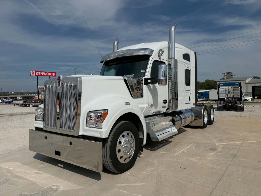 Kenworth W990 conventional sleeper tractor in white showing front grille and driver side with dual stacks.