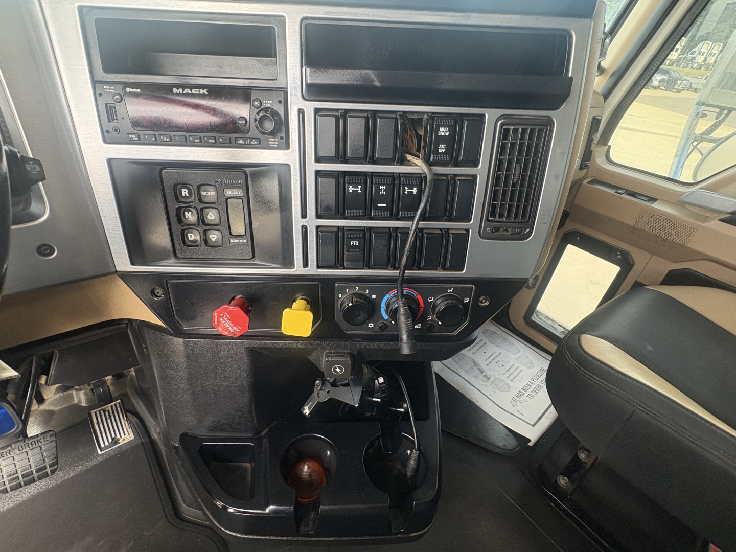 Truck cockpit of a 2022 Mack GR64F showing dashboard with controls, radio, switches, ignition area, gear shifter, and steering column.