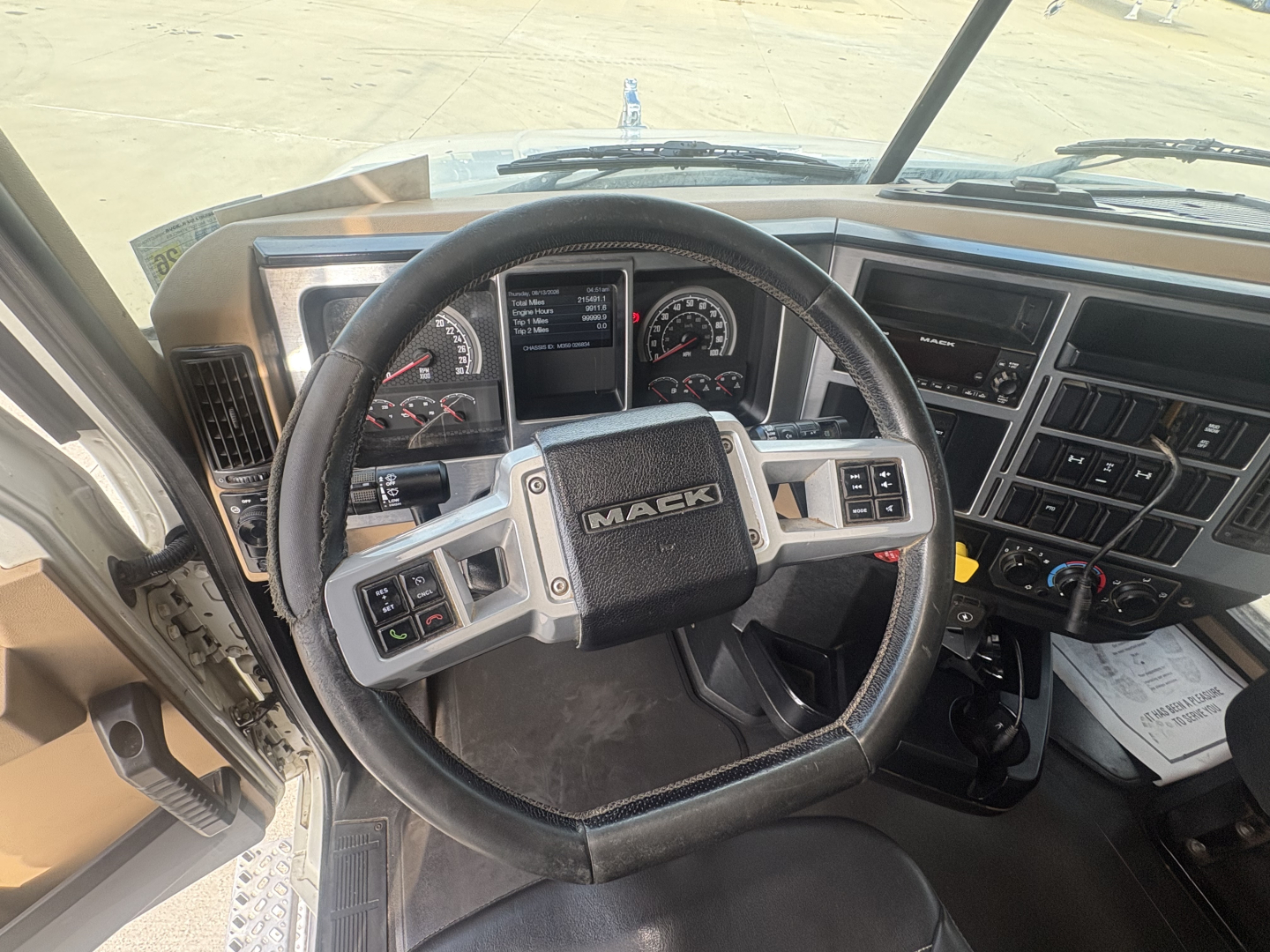 Dashboard and steering wheel of a Mack GR64F dump truck interior with controls and gauges visible.