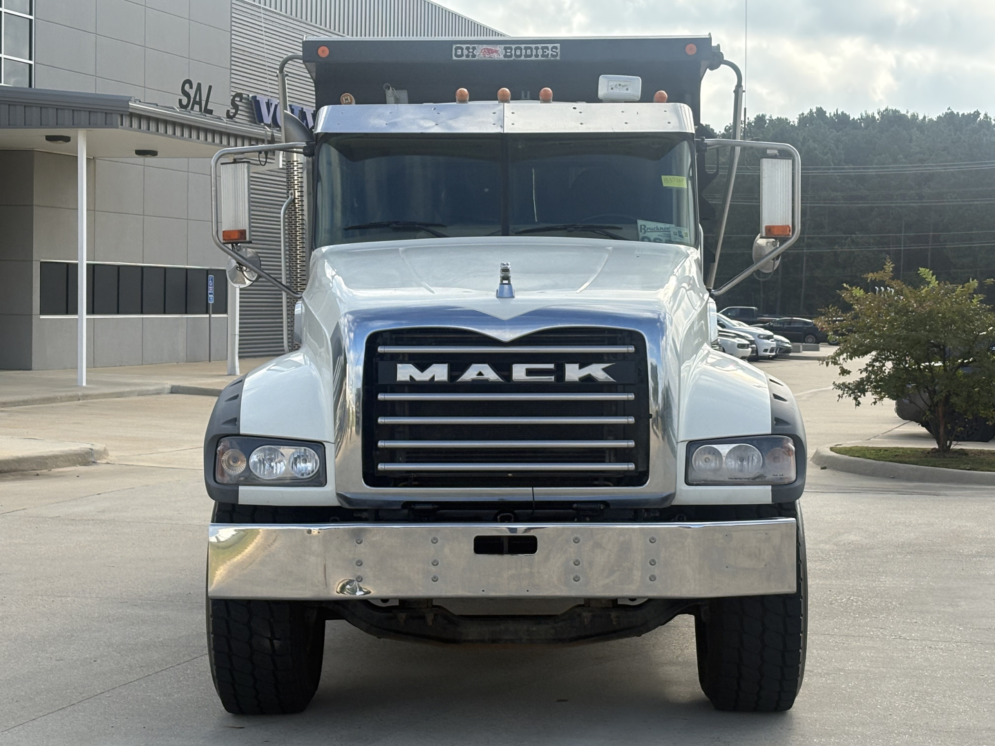 Front view of a 2022 Mack GR64F dump truck showing large chrome bumper, black grille with MACK lettering, dual headlights, and mirrors.