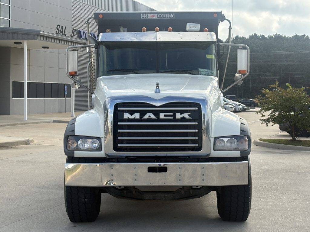 Front view of a 2022 Mack GR64F dump truck showing large chrome bumper, black grille with MACK lettering, dual headlights, and mirrors.