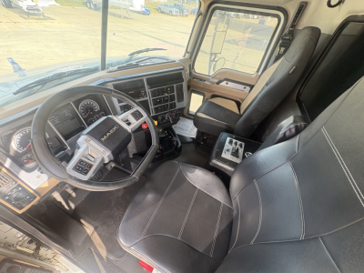 Mack GR64F truck cab interior showing steering wheel, dashboard, and driver seat with controls and passenger seat.