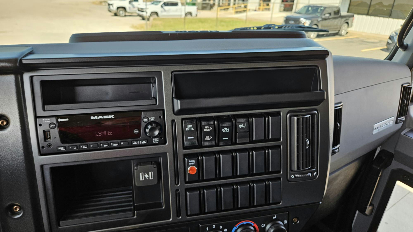 Dashboard of a 2025 Mack MD6 showing radio, climate controls, and switch panels in a box truck cab.