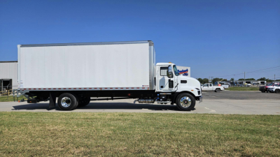 Box truck side view showing a white 2025 Mack MD6 with a large rectangular cargo box, cab at front, daytime parking lot in background.