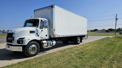 Mack MD6 box truck in a parking lot showing cab and large box cargo area.