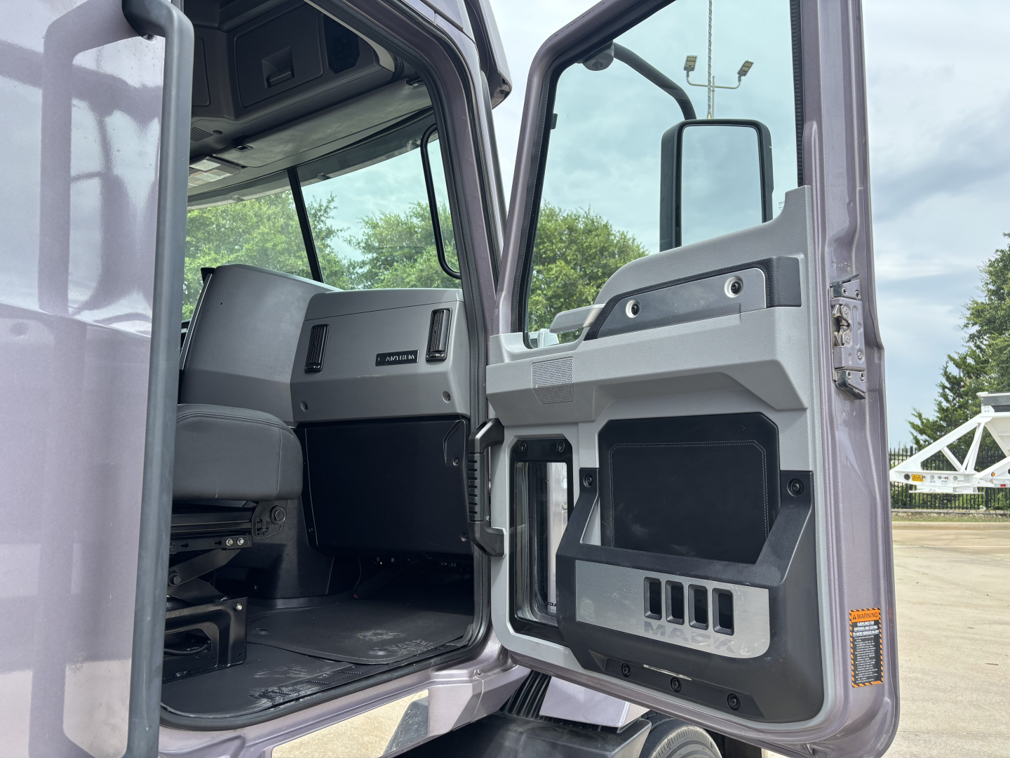 Truck cabin interior showing driver's door and dashboard area of a 2023 Mack AN64T70 tractor.