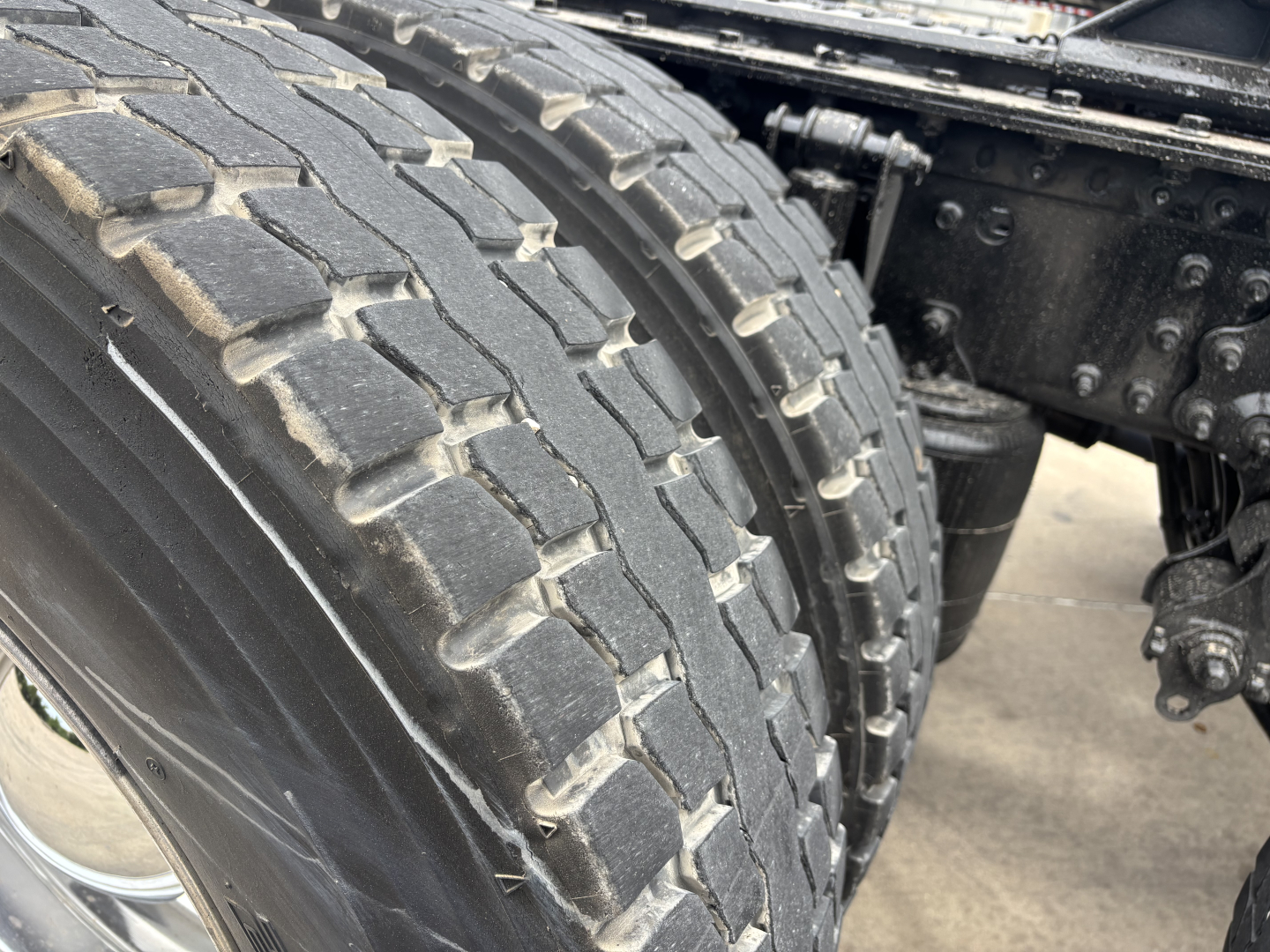 Dual rear tires on Mack AN64T70 sleeper truck showing tread and wheel area.