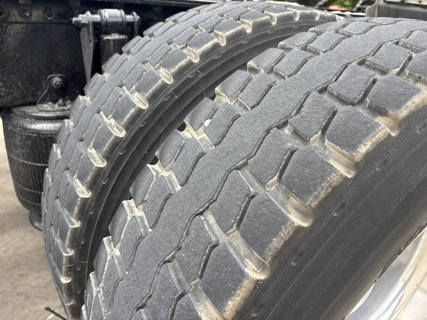Tire tread and side area of a Mack AN64T70 truck showing dual rear tires and suspension components.