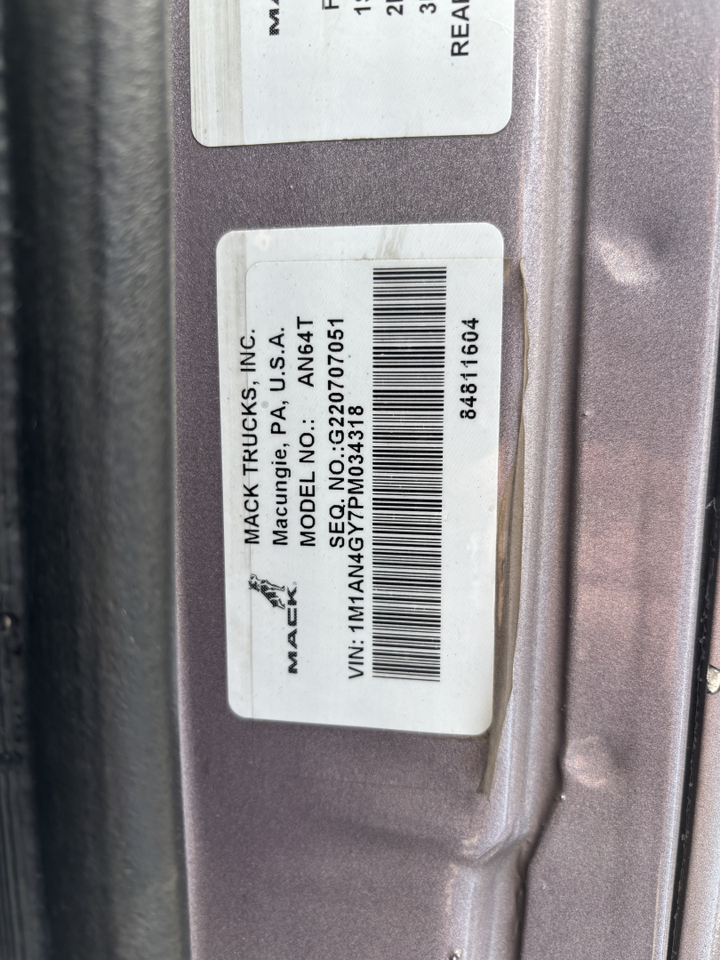Label on Mack truck door jamb showing vehicle and model details: 'MACK TRUCKS INC. MODEL NO. AN64T70 VIN: 1M1AN4GY7PM034318' with barcode and serial lines.