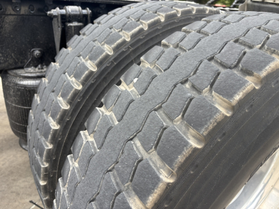 Tire tread and side area of a Mack AN64T70 truck showing dual rear tires and suspension components.