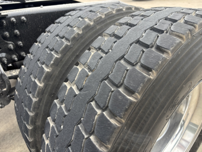 Mack AN64T70 truck wheel and tire close-up showing rugged tread and black metal rim.