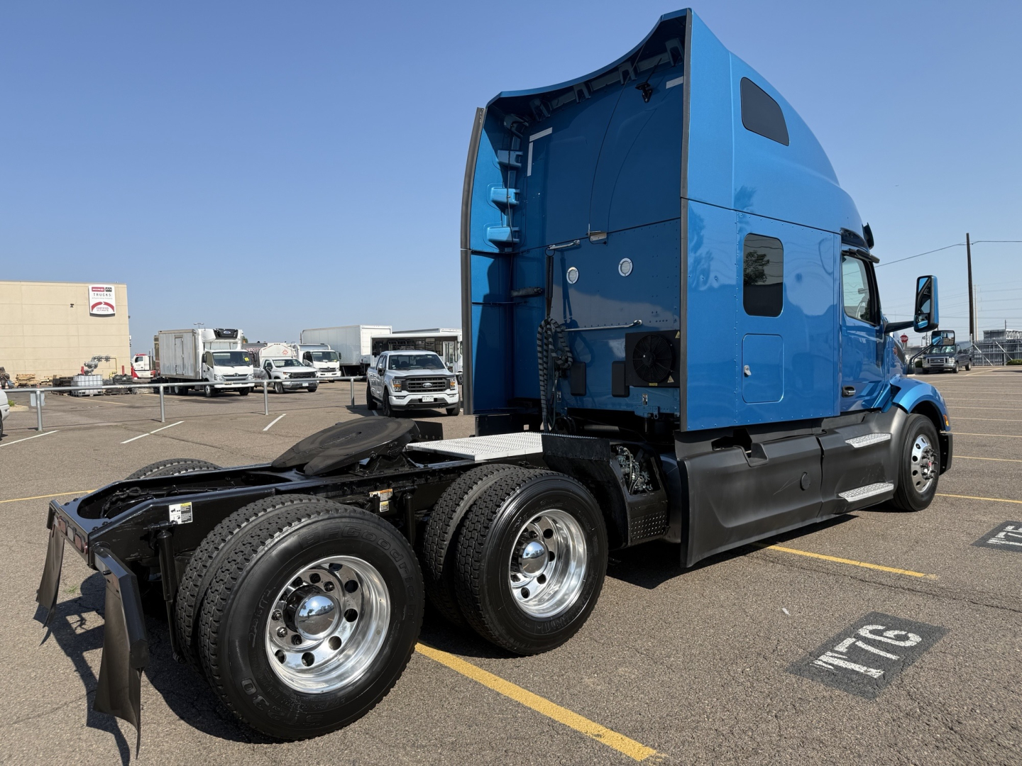 Peterbilt 579 truck cab in blue with sleeper, rear view shows dual rear axles and fifth wheel, side view shows VIN and stock number not visible on image